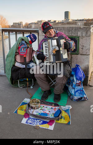 In una fredda giornata invernale un musicista di strada di suonare la fisarmonica per cambio di ricambio sul Pont Saint Louis di Parigi, Francia. Foto Stock