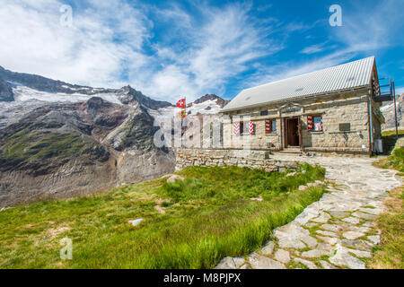 Swiss rifugio capanna alpina alla fine del sentiero di Grimsel ghiacciaio. Impressionante gamma di montagna avvolge la valle. Foto Stock