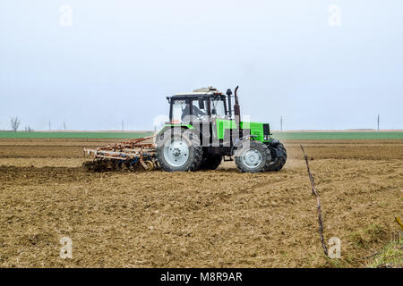 Rigogliosa e allentare il suolo sul campo prima della semina. Il trattore aratri un campo con un aratro Foto Stock