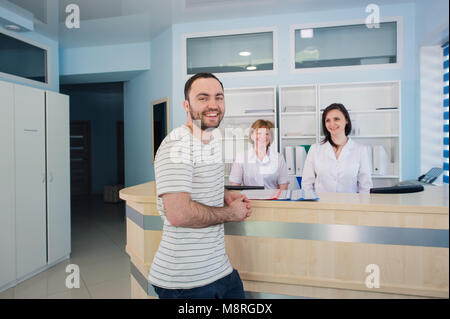Paziente di sesso maschile con medico e infermiere presso la reception in ospedale Foto Stock