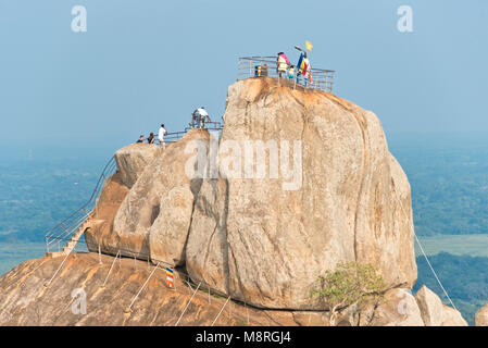 Aradhana rock Gala Mihintale opposta che i pellegrini e i turisti salgono a pregare o guardare la vista su una giornata soleggiata con cielo blu. Foto Stock