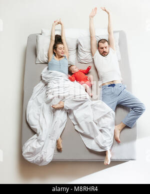 Vista superiore della famiglia felice con un neonato in camera da letto. Foto Stock