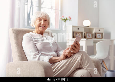 Bella donna sorridente navigando in Internet sul suo telefono Foto Stock