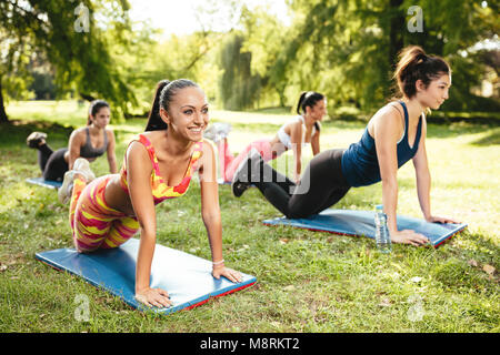 Quattro bella femmina motivati amici facendo push-up nel parco della città. Foto Stock