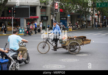 Persone a cavallo delle biciclette e scooter per le strade di Shanghai in Cina Foto Stock