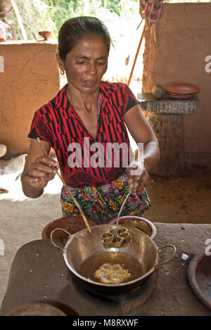 Un locale accogliente dello Sri Lanka donna la preparazione di prodotti alimentari tradizionali (Kokis) a casa sua, una piccola fattoria appena fuori di Sigiriya. Foto Stock