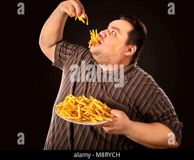 Fat man di mangiare fast food patatine fritte per persona in sovrappeso. Foto Stock