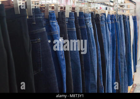 Jeans su staffe sono venduti nella boutique di moda di mercato di abbigliamento Foto Stock