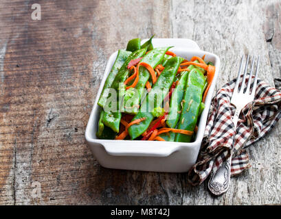 Green fagiolini e carote con spezie sul tavolo di legno Foto Stock