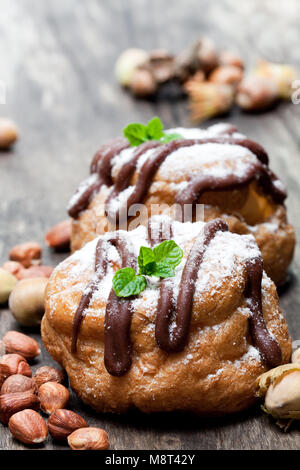 Il cioccolato belga choux panini farciti con crema alla nocciola sulla tavola di legno Foto Stock