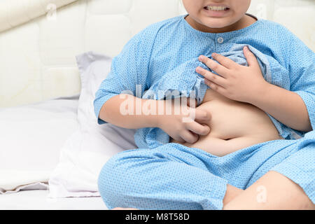 Graffiare il suo ventre in soggetti obesi boy sul letto, health care concept Foto Stock