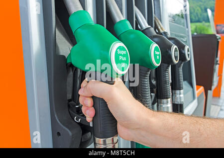 Un maschio di mano che tiene una pompa a gas ugello in corrispondenza della stazione di gas Foto Stock