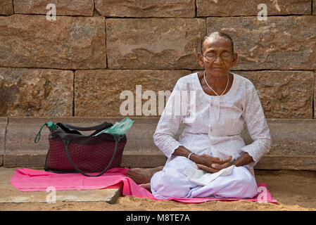 Un anziano dello Sri Lanka donna, pregando e meditando a Jaya Sri Maha Bodhi in Anuradhapura, Sri Lanka. Foto Stock