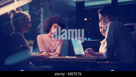 Multietnica startup business team sulla riunione di notte moderno ufficio brainstorming interiore, lavorando sul computer portatile Foto Stock