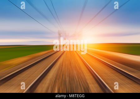 La ferrovia in movimento al tramonto. Moto concetto sfocata l'immagine. Foto Stock