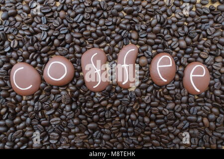 Caffè, concettuale composizione artistica con brown pietra dipinta lettere oltre i chicchi di caffè Foto Stock