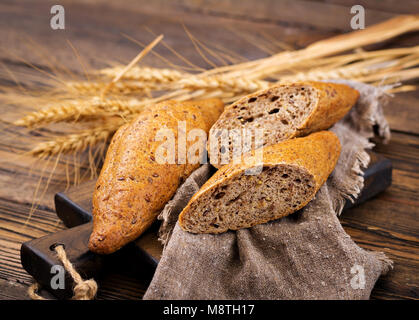 Panini dolci di tutto il grano in farina con aggiunta di semi di lino su uno sfondo di legno. Foto Stock