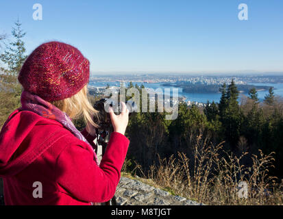 Fotografo donna che scatta una fotografia con la sua fotocamera reflex digitale dal Cypress Mountain Lookout a West Vancouver, BC, Canada. Foto Stock