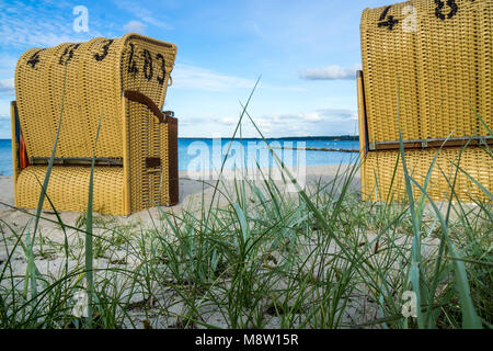 Sedie di vimini sulla spiaggia in piedi pronto per l'estate i visitatori nella sabbia Foto Stock