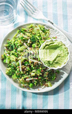 La quinoa & supergreen insalata. Broccoli, piselli, il ravanello & quinoa con houmous & spinaci dip Foto Stock