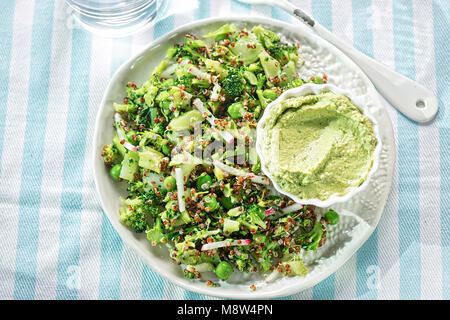 La quinoa & supergreen insalata. Broccoli, piselli, il ravanello & quinoa con houmous & spinaci dip Foto Stock