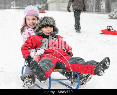 Giovane kids, un ragazzo e una ragazza sono corse in slittino in una fredda giornata invernale Foto Stock