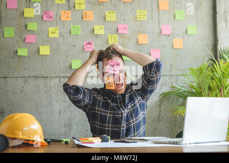 Ha sottolineato l'uomo con il messaggio su foglietti adesivi sul suo volto in ufficio. Foto Stock