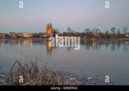 Gniezno, Polonia; vista serale per la cattedrale gotica sul lago ghiacciato. L'inverno. Foto Stock