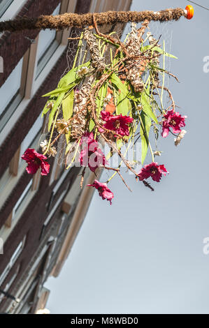 Un bouquet di fiori appesi da un pennone su un muro di una casa Foto Stock