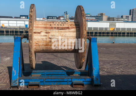 Grande puleggia di legno su una piattaforma in acciaio presso la banchina del porto Foto Stock