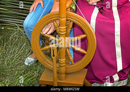 In legno antico ruote di filatura e di una donna in costume nazionale. Foto Stock