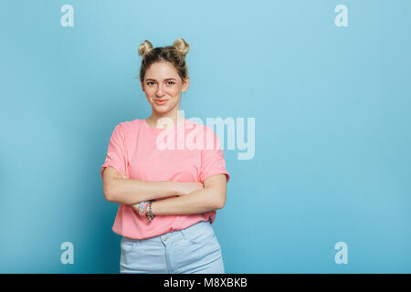 Giovane donna in una t-shirt rosa su sfondo blu Foto Stock