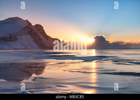 Vista panoramica di colorato tramonto su winter seascape. Sun spiata attraverso le nuvole in una fredda mattina di inverno. Foto Stock