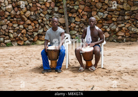 L'uomo africano giocando sui tamburi di bongo, il modo tradizionale di musica, essi svolgono anche per turisti nei rifugi Foto Stock