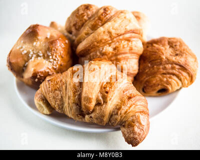 Primo piano di una varietà di croissant e panini su una piastra bianca e la tabella Foto Stock