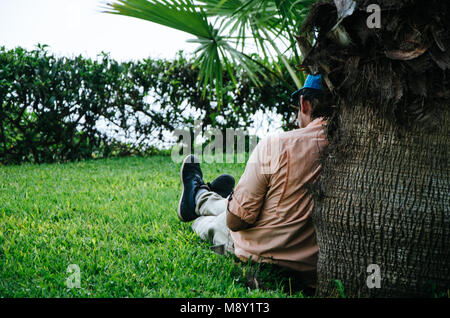 Uomo appoggiato sul tronco di un albero Foto Stock