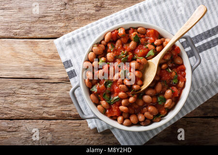 Stufati di mirtillo palustre o di fagioli borlotti in salsa di pomodoro con erbe di close-up in una ciotola sul tavolo. parte superiore orizzontale vista da sopra Foto Stock