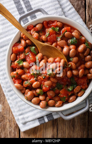 Organici di fagioli borlotti in salsa di pomodoro con erbe di close-up in una ciotola sul tavolo. Verticale in alto vista da sopra Foto Stock