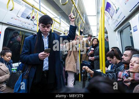 Pendolari che viaggiano per lavorare su una Londra metropolitana treno. Foto Stock