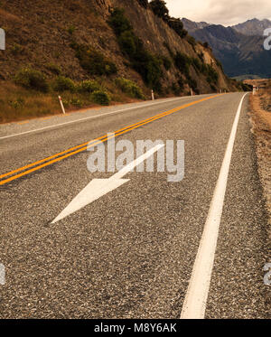 Freccia bianca segno di traffico, giallo linee divisorie e sentiero bianco linea sull'asfalto stradale rurale Foto Stock