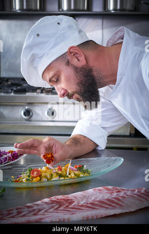 Chef fiore di farcitura in ceviche piatto con mani in acciaio inox cucina Foto Stock