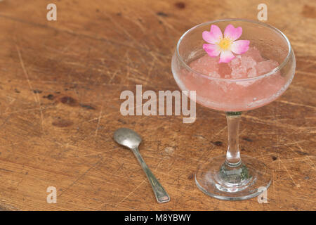 Congelati vino rosato in un dessert di vetro con un cucchiaio e organici di petali di rosa Foto Stock