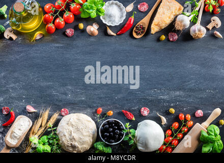 Pizza ingredienti sulla tavola nera in un Raw - il cibo italiano Foto Stock