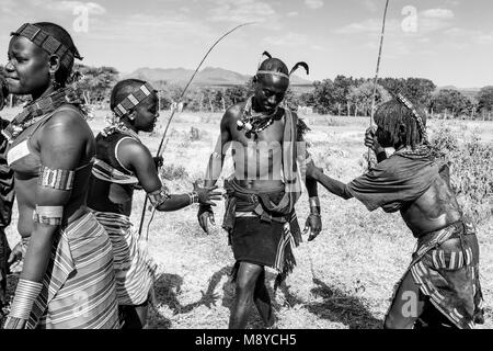 Giovani donne Hamar Taunt A Hamar Tribesman alla fustigazione a loro in un 'proveniente dall'età' Bull Jumping cerimonia, Dimeka, Valle dell'Omo, Etiopia Foto Stock