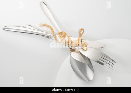 Posizionare l'impostazione close up. Forcella, un cucchiaio e un coltello sulla piastra bianca. Angolo di visione, il fuoco selettivo Foto Stock