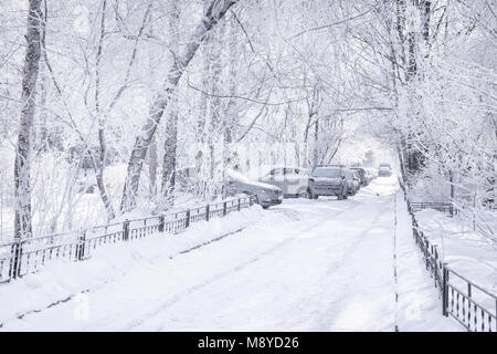 Winter City scena. Il bianco della neve-cortile coperto con le automobili e strada vuota. Tasto alto Foto Stock