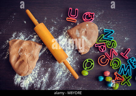 Pasqua la cottura di preparazione. Impasto crudo, mattarello e frese per la vacanza i cookies al buio su un tavolo di legno. Uova di Pasqua. Pasqua gastronomica concetto. Top vi Foto Stock