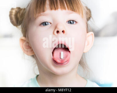 Chiusura del bambino mette la pillola nella sua bocca Foto Stock