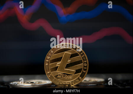 Un Litecoin cryptocurrency è visto di fronte il mercato azionario grafici Foto Stock