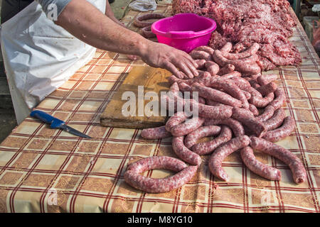 Il macellaio rende salsicce fatte in casa all'aperto in un modo tradizionale. Foto Stock